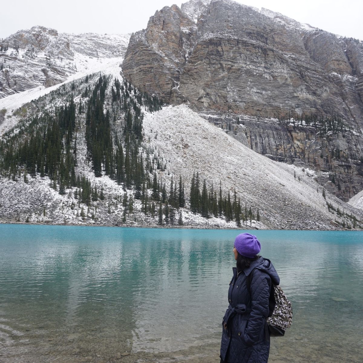 woman looking towards mountain beside a lake