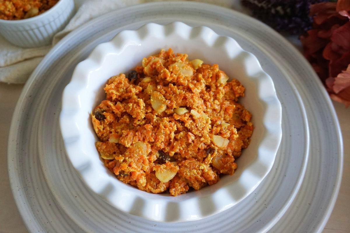 Carrot halwa in a white bowl on white plate.